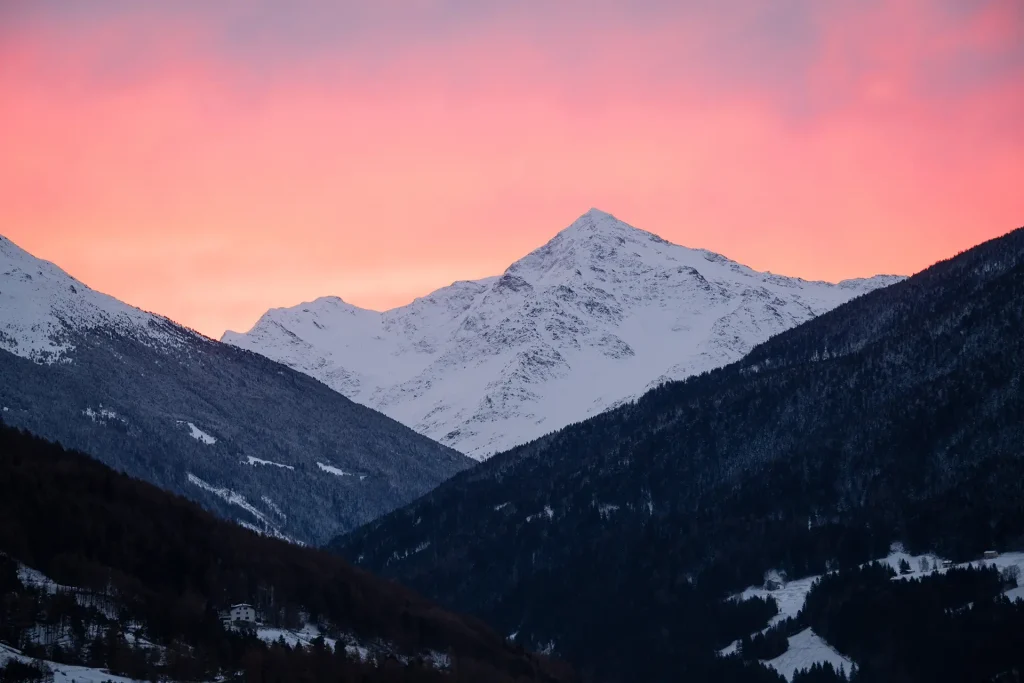Tramonto su una montagna innevata con un cielo rosa.