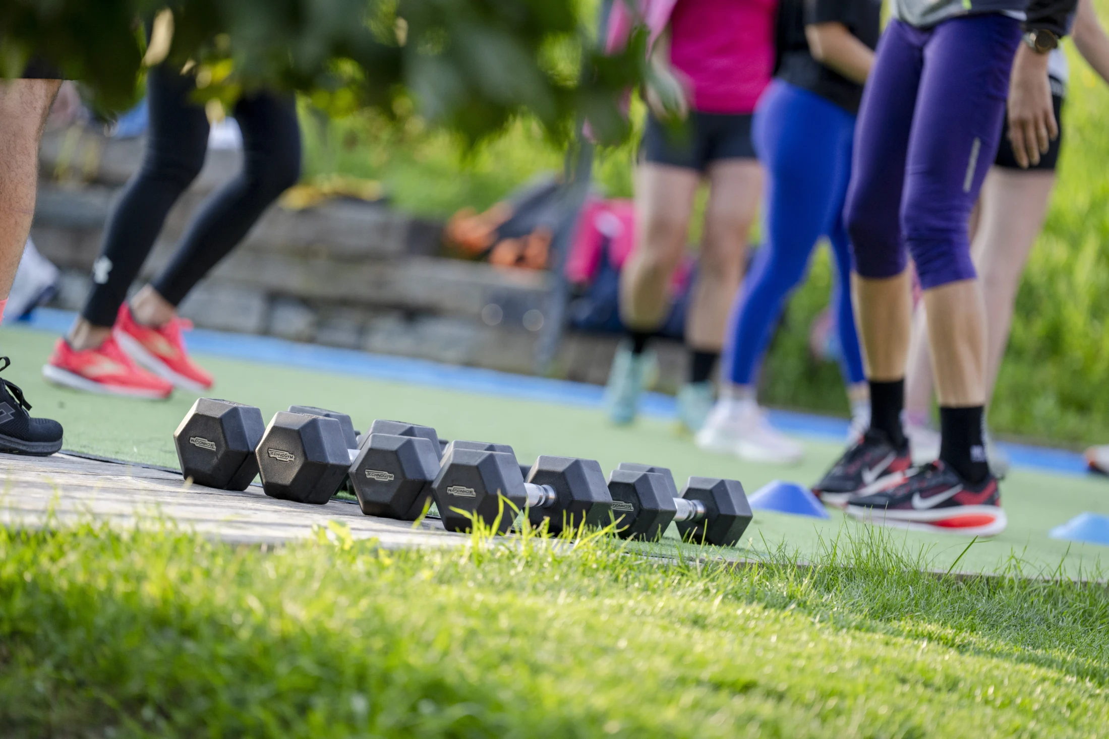 A group exercising outdoors with dumbbells on the grass.