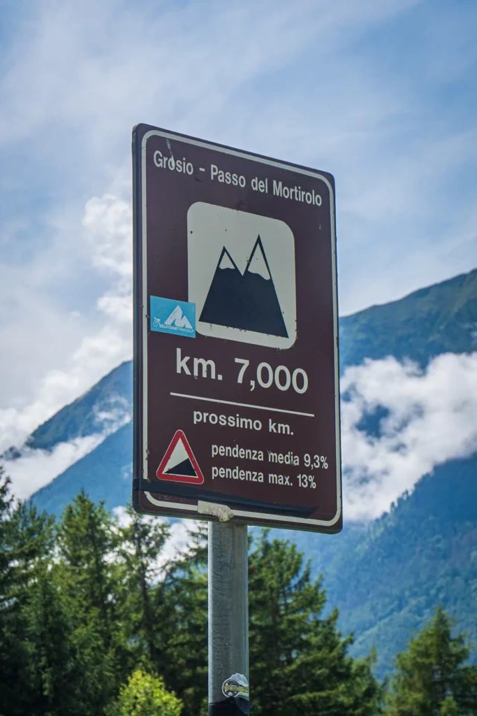 Cartello stradale del Passo del Mortirolo con indicazioni di chilometraggio e pendenza.