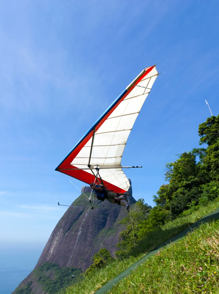 A person hang gliding near a mountain under a clear blue sky.
