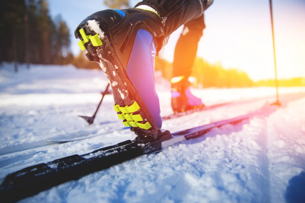 Close-up of a person's boot on a ski in snowy conditions.