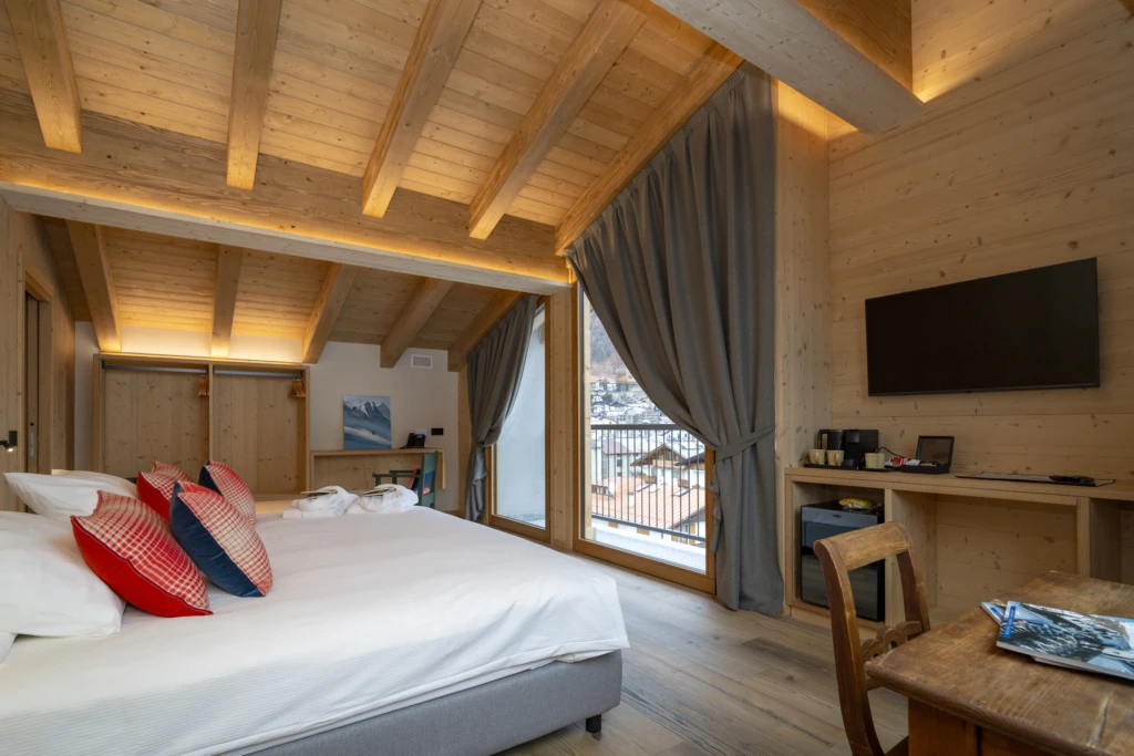 Camera da letto moderna e accogliente con soffitto in legno, grandi finestre e arredamento elegante.