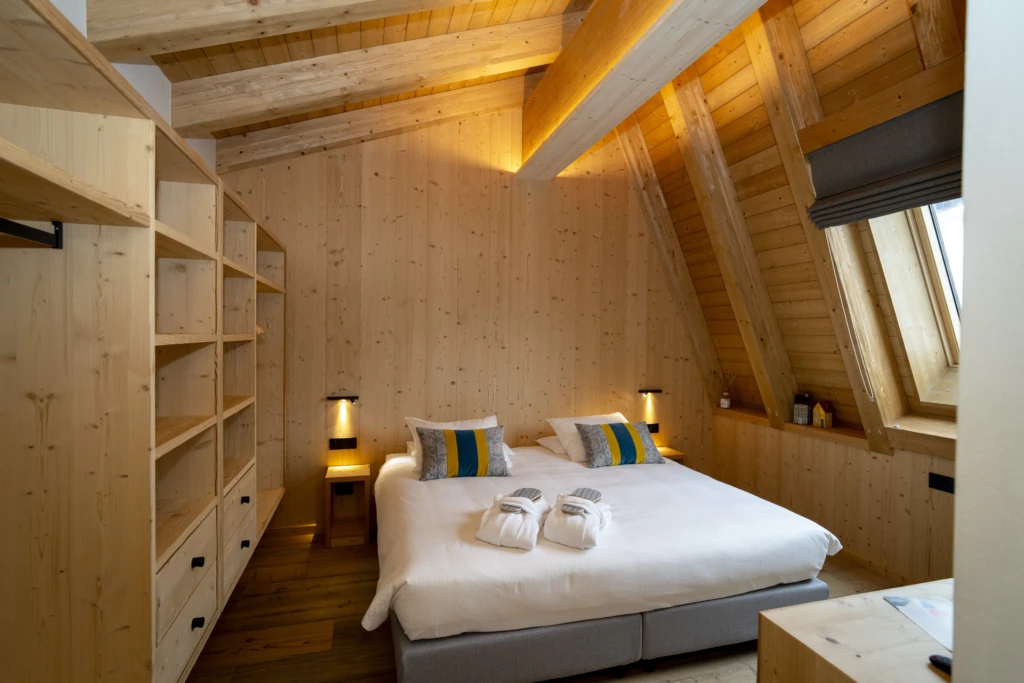 Camera da letto accogliente in legno con letto matrimoniale e illuminazione soffusa.