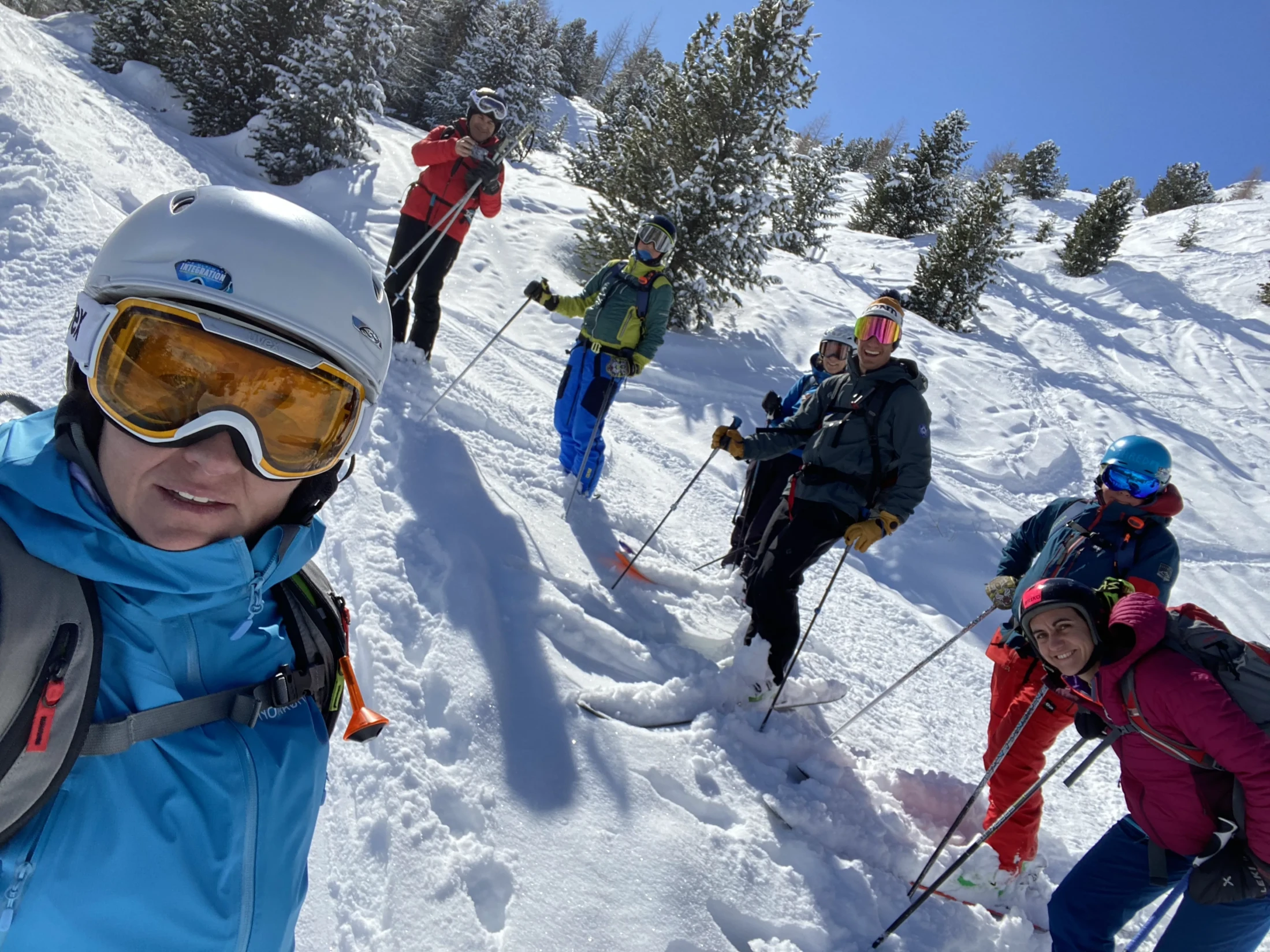 Un gruppo di sciatori sorridenti su una pista innevata sotto un cielo sereno.
