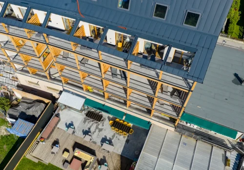 Vista aerea di un edificio moderno con strutture in legno e terrazza esterna attrezzata.