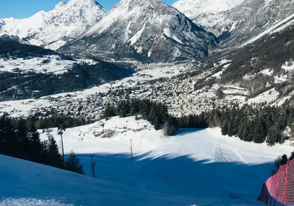Pista da sci innevata con vista su montagne maestose e cielo azzurro.