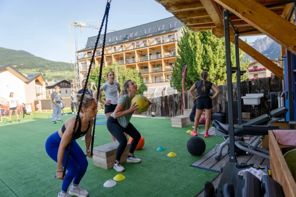 Persone che si allenano all'aperto con attrezzi fitness in un'area verde.