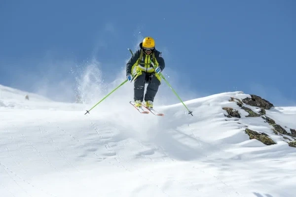 Scialpinista in azione mentre scende da una montagna innevata.
