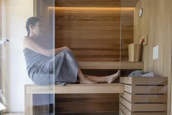 A person sitting in a wooden sauna wrapped in a towel.